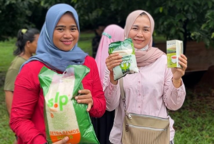 Masyarakat menunjukkan beras premium dan bahan makanan murah yang dibeli saat gebyar pasar murah Pupuk Kujang  